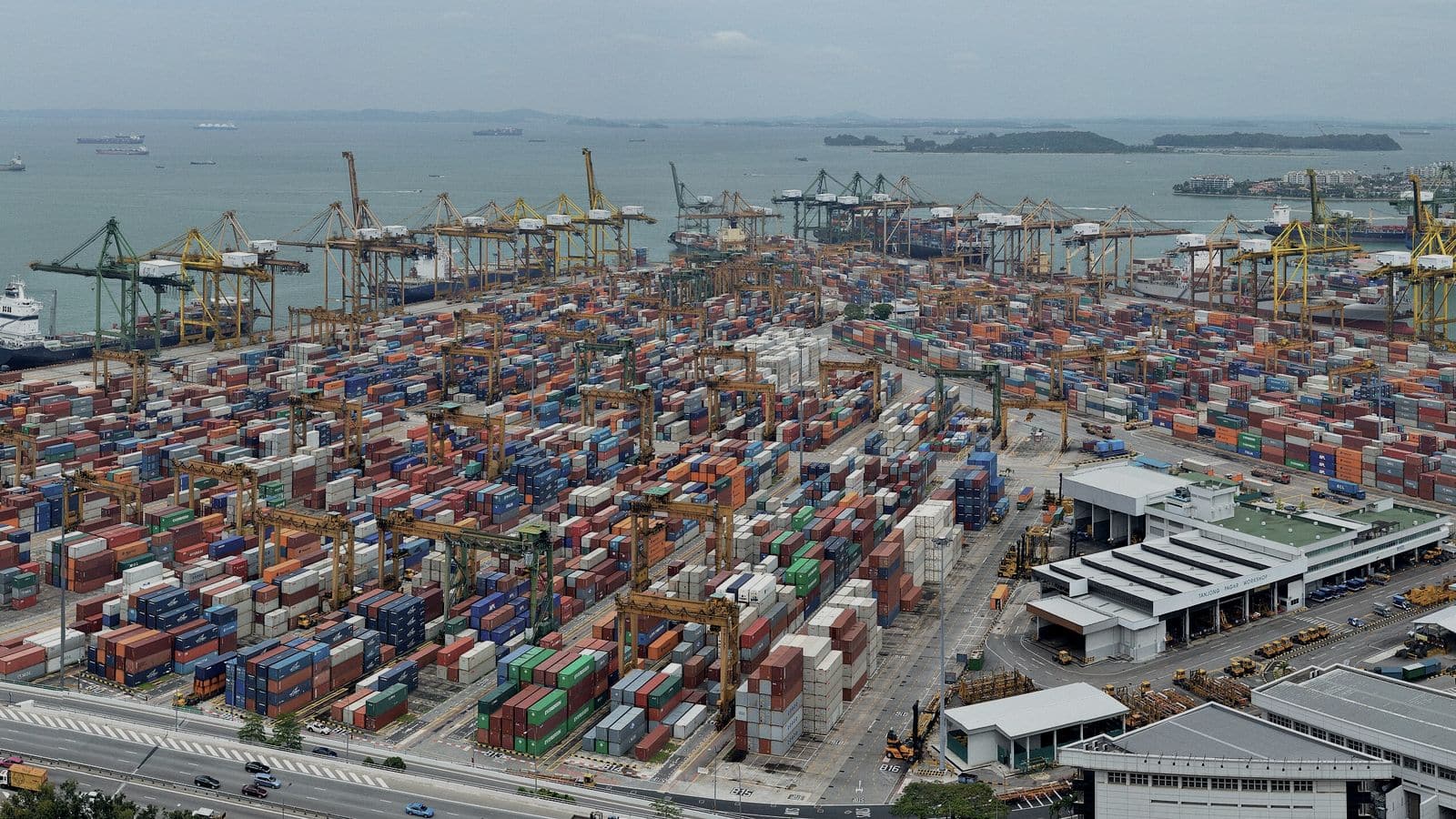 Container terminal seen from above, stacked boxes and gantry cranes along the quay